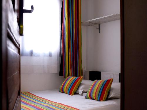 a bedroom with a bed with two colorful pillows on it at Hotel Sakamanga in Antananarivo
