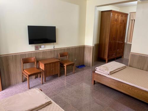 Una habitación con una cama y dos sillas y un televisor. en Baviecoresort, en Ba Vì