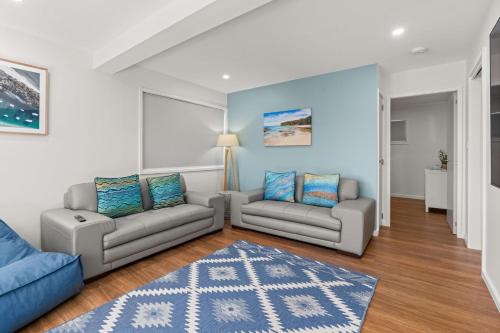 a living room with two couches and a rug at Baxter's Beach House by Experience Jervis Bay in Vincentia
