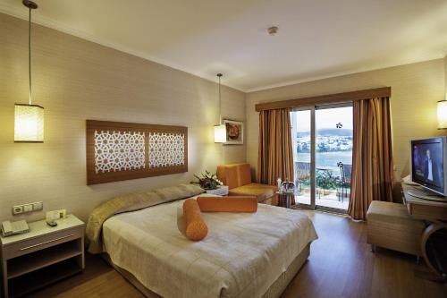een hotelkamer met een bed en een televisie bij Royal Asarlik Beach Hotel in Gümbet