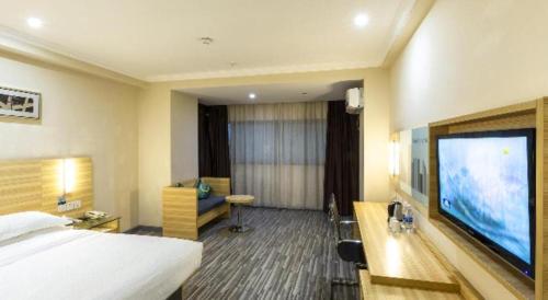 a hotel room with a bed and a flat screen tv at City Comfort Inn Wuhan Zhongnan Road Metro Exit in Wuhan