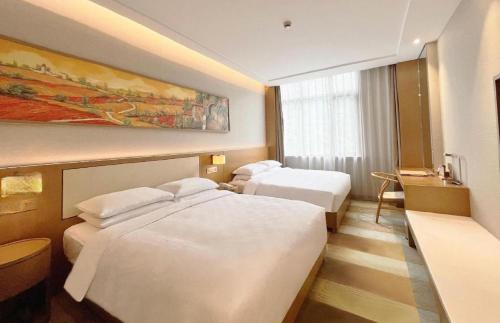 a hotel room with two beds and a desk at Deefly Yinrun Town Hotel in Deqing