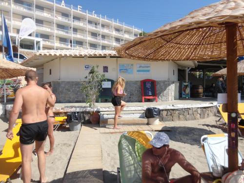 a group of people in the sand at a beach at New Aegli Resort Hotel in Poros