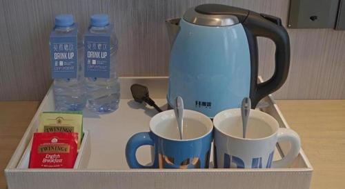 a tea kettle and two cups of coffee on a tray at Echarm Hotel Kunming High-speed Railway South Station Chunrong Street Metro Station in Kunming