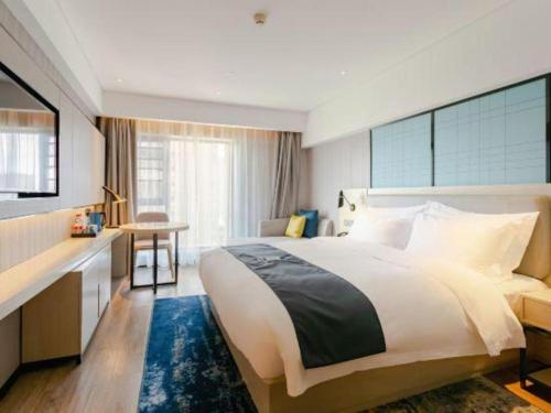 a bedroom with a large bed and a desk at Echarm Hotel Kunming High-speed Railway South Station Chunrong Street Metro Station in Kunming