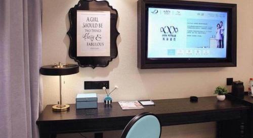 an office with a desk with a tv on the wall at Xana Hotelle Shenzheng South Station Foxconn in Shenzhen