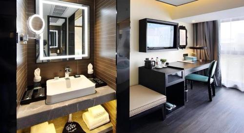 a bathroom with a sink and a desk with a television at Xana Hotelle Shenzheng South Station Foxconn in Shenzhen