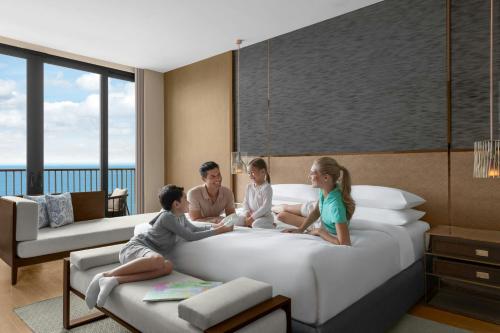 a family sitting on a bed in a hotel room at Sheraton Cebu Mactan Resort in Mactan