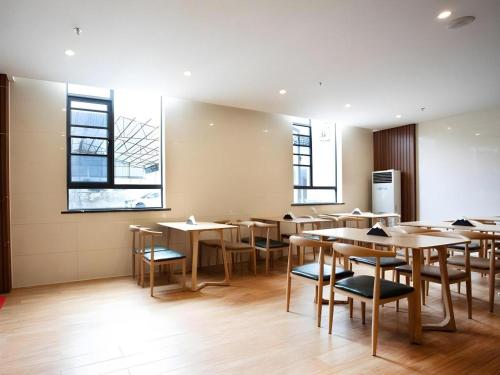 a dining room with tables and chairs and windows at GreenTree Inn Linhai Jiangnan Avenue Express in Linhai