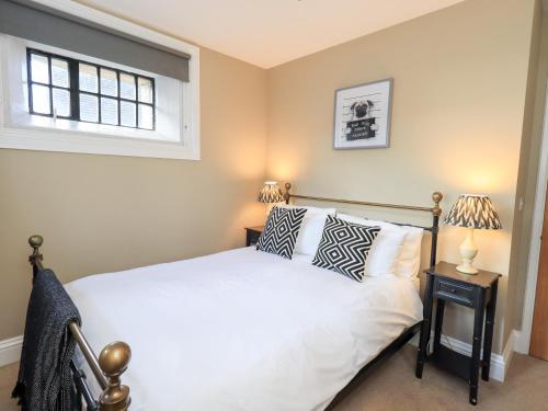 a bedroom with a bed with two lamps and a window at The Cells in Ingleton 