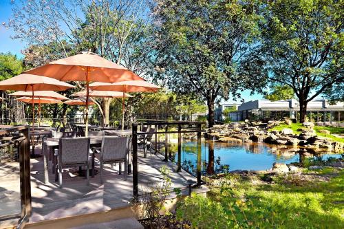 a patio with tables and umbrellas next to a pond at Sheraton Montreal Airport Hotel in Dorval