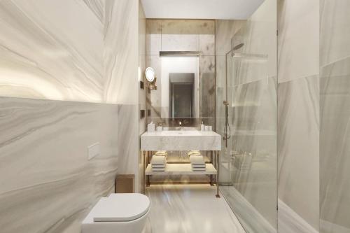 a white bathroom with a sink and a toilet at The Marmorosch Bucharest, Autograph Collection in Bucharest