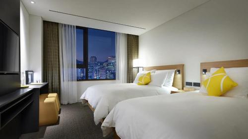 a hotel room with two beds and a large window at L7 MYEONGDONG by LOTTE in Seoul