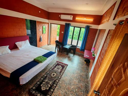 オーロヴィルにあるSrishti Guest Houseのベッドと机と窓のある寝室