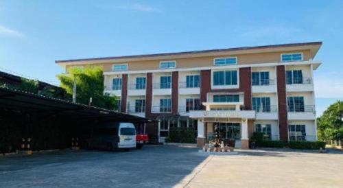 a large building with a van parked in a parking lot at Niwtara Place Lom Sak Hotel in Phetchabun