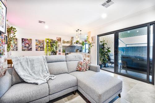 a living room with a gray couch and a kitchen at Luxe Cosy Room in Beechboro in Perth