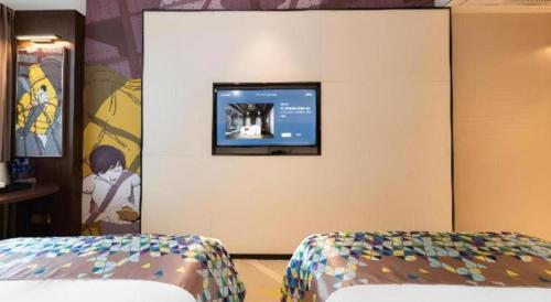 a bedroom with a tv on the wall and a bed at Borrman Hotel Wuhan Hankou Railway Station Metro Station in Wuhan