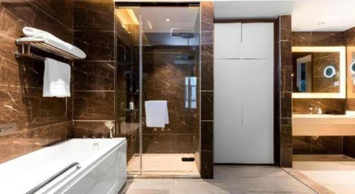 a bathroom with a tub and a shower with a glass door at Borrman Hotel Wuhan Hankou Railway Station Metro Station in Wuhan