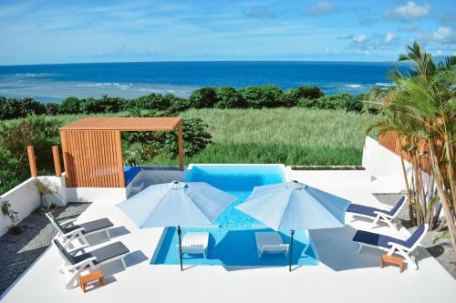 a patio with chairs and umbrellas and the ocean at Ocean View Ishigaki Kaze and Nami in Ishigaki Island