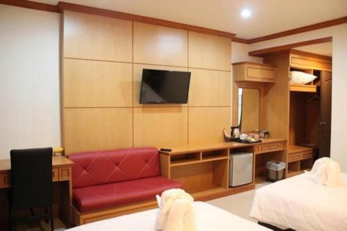a hotel room with a red couch and a tv at Siamtara Palace Hotel in Maha Sarakham