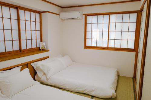 two beds in a room with two windows at Akira Hiro House - Room101 in Tokyo