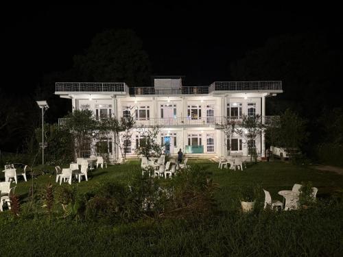 a large white house with white lawn chairs at night at Moustache Hostel Bir in Bīr