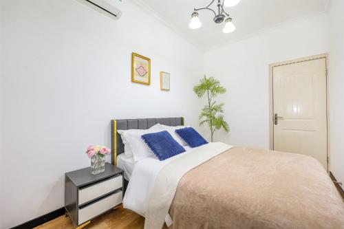 a white bedroom with a bed with blue pillows at Baihong Riverview Apartment-Hongya Cave in Chongqing