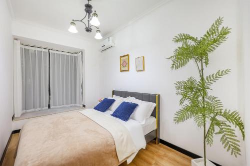 a bedroom with a bed with blue pillows and a plant at Baihong Riverview Apartment-Hongya Cave in Chongqing