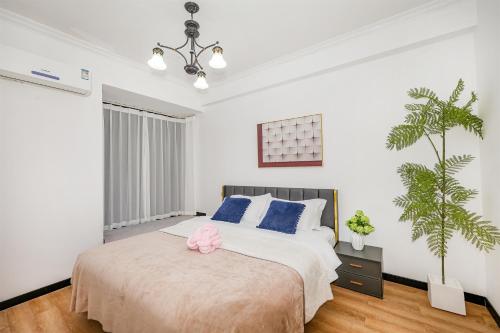 a bedroom with a large bed with blue pillows and a plant at Baihong Riverview Apartment-Hongya Cave in Chongqing