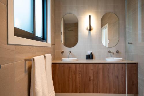 a bathroom with two sinks and two mirrors at Moritz Hahndorf Boutique Guest House in Hahndorf