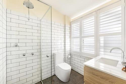 a white bathroom with a toilet and a sink at Canungra Hotel in Canungra