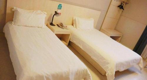 two beds in a hotel room with white sheets at Jinjiang Inn Jiaxing South Lake in Jiaxing