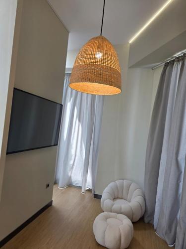 a living room with two white ottomans and a hanging light at Cape of Rodon Resort, Green Village in Draçi