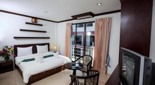 a bedroom with a bed and a television and a balcony at Triple Rund Place Hotel in Patong Beach