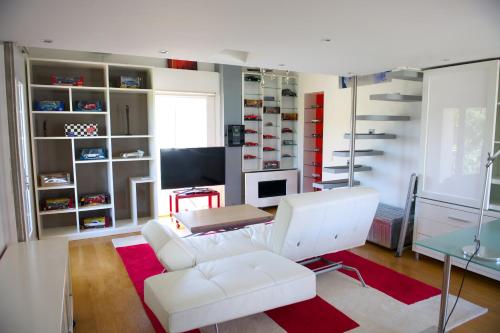 a living room with a white couch and a television at Maison d'Elie in Saint-Tropez