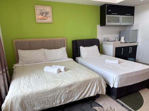 two beds in a room with green walls at The Viana Apartment 6 in Kota Bharu