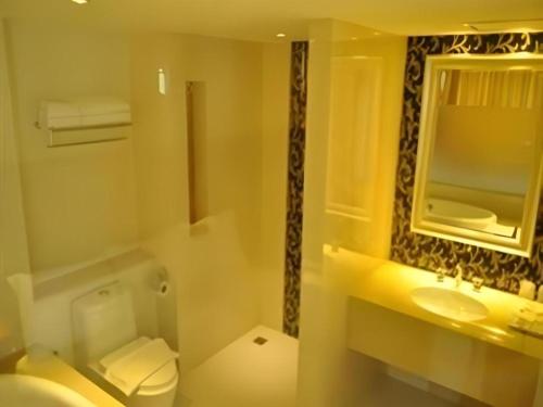 a bathroom with a toilet and a sink and a mirror at Aramis Hotel in Nakhon Sawan