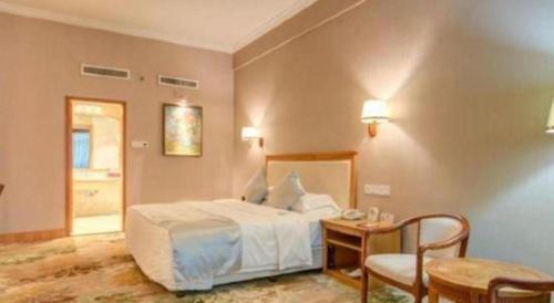 a bedroom with a bed and a table and chairs at Zhuhai Dehan Hotel in Zhuhai