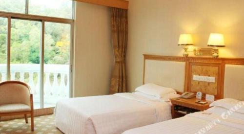 a hotel room with two beds and a window at Zhuhai Dehan Hotel in Zhuhai