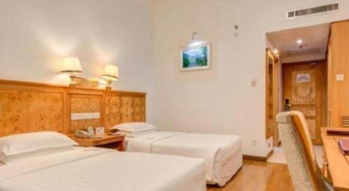 a hotel room with two beds and a desk at Zhuhai Dehan Hotel in Zhuhai