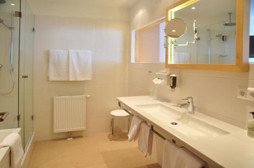 ein weißes Bad mit einem Waschbecken und einer Dusche in der Unterkunft Alpenrose Kufstein in Kufstein