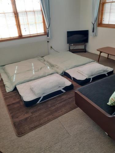 a room with three beds in a room with a tv at ゲストハウス苫小牧 203号室 in Tomakomai