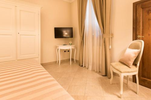 a bedroom with a bed and a chair and a television at Residenza Marchesi Pontenani in Florence