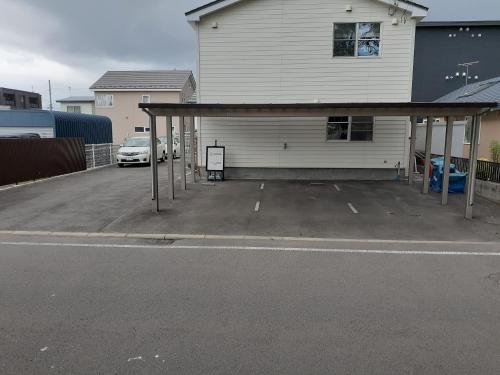 a parking lot in front of a white house at ゲストハウス苫小牧 203号室 in Tomakomai