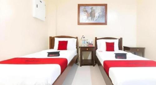 two beds in a room with red and white sheets at Dino Residences in Dumaguete