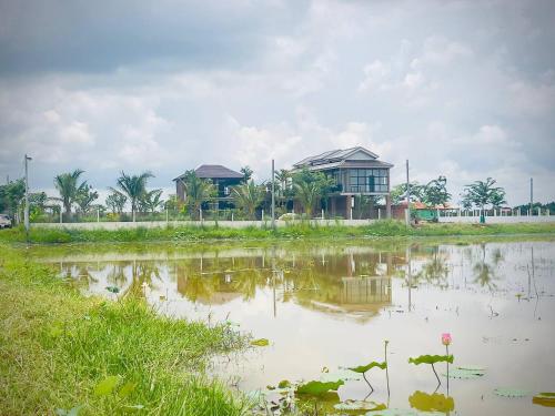 a house in a field next to a body of water at Sanctuary Home Stay in Phumĭ Don Téav