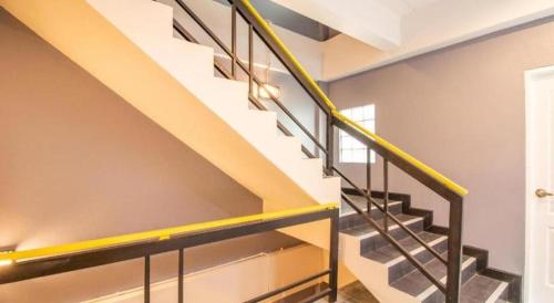 a staircase in a house with a yellow rail at OYO 726 Sookjai Cafe and Hostel in Chiang Mai