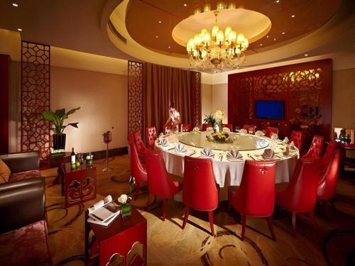 a dining room with a large table and red chairs at New Century Hotel Taizhou 