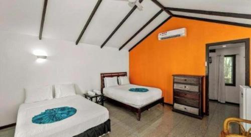 a bedroom with two beds and an orange wall at Orator Hotel in Apia