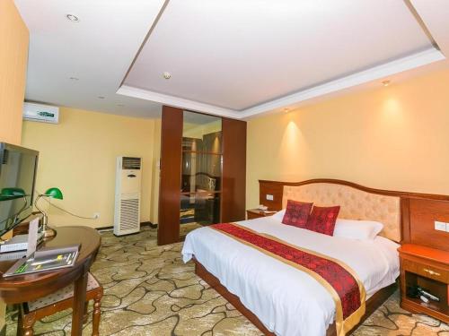 a hotel room with a bed and a desk and a desk at GreenTree Alliance Zhejiang Zhoushan Putuoshan Zhujiajian Scenic Spot Hotel in Zhoushan